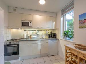 a kitchen with white cabinets and a sink at Holiday Home near Dutch Beach with Pool in Sint Maartensvlotbrug
