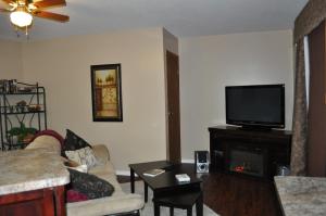 a living room with a couch and a tv and a fireplace at Garden House in Courtenay