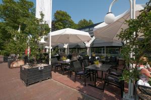 eine Terrasse mit Tischen, Stühlen und Sonnenschirmen in der Unterkunft Hotel De Rustende Jager in Nieuw-Vennep