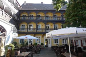 un bâtiment jaune avec des tables et des parasols devant lui dans l'établissement Apart-Hotel Heiligenthaler Hof, à Landau in der Pfalz