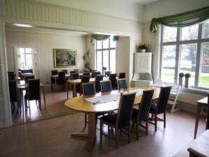un comedor con mesas, sillas y ventanas en Ediths Pensionat en Karlsborg