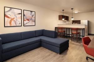 a living room with a blue couch and a kitchen at Hyatt Studios Kalispell in Kalispell