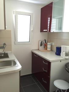 eine kleine Küche mit einem Waschbecken und einem Fenster in der Unterkunft Villa Radoš - 4 Sterne, 4 Apartments für maximal 22 Gäste in Supetar