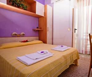 a bedroom with a yellow bed with towels on it at Hotel Moja in Cesenatico