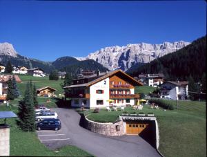 a town with cars parked in a parking lot with mountains at Garni Waltoy in Selva di Val Gardena