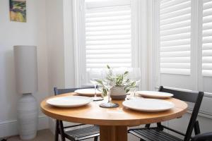 a wooden table with plates and glasses on it at Pebble Hideaway in Worthing