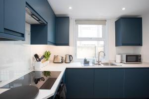 a kitchen with blue cabinets and a sink at Pebble Hideaway in Worthing +49 photos