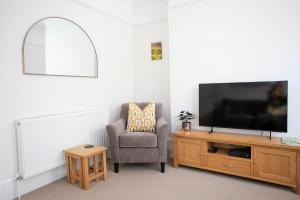 a living room with a chair and a flat screen tv at Pebble Hideaway in Worthing