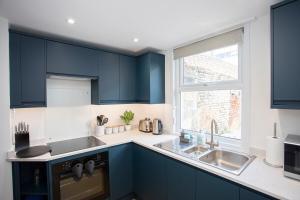 a kitchen with blue cabinets and a sink and a window at Pebble Hideaway in Worthing