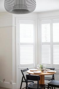 a dining room with a table and chairs and windows at Pebble Hideaway in Worthing