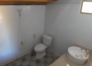 a white bathroom with a toilet and a sink at anisa homestay and restaurant in Ekas