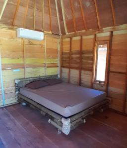 a bed in a wooden cabin with a window at anisa homestay and restaurant in Ekas