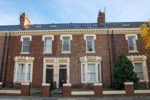 a red brick building with a black roof at Flex Lets - Azalea Terrace Apartments in Sunderland