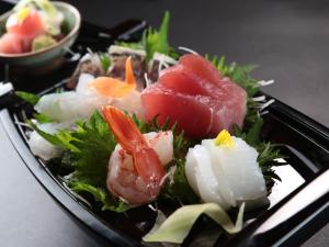a black plate of food with sushi and vegetables at 港の魚宿 おおそね in Owase