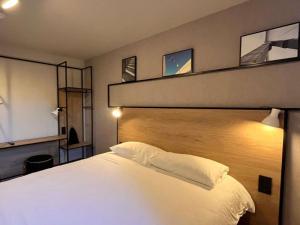 a bedroom with a large white bed with a wooden headboard at ibis Toulouse Aeroport in Blagnac +136 photos