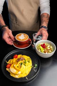 a man holding a plate of food and a cup of coffee at The Lubo - self check-in in Lucerne