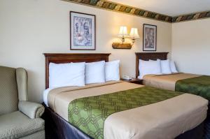 a hotel room with two beds and a chair at Rodeway Inn Vicksburg in Vicksburg +18 photos