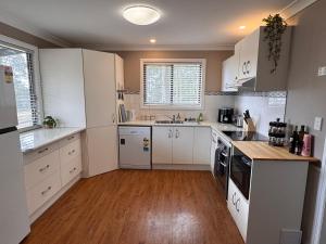 a kitchen with white cabinets and a wooden floor at Singleton Rose Cottages in Singleton