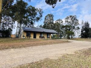 a yellow house with a black roof on a dirt road at Singleton Rose Cottages in Singleton