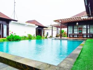 a swimming pool in front of a house at Merlyn Meadows Retreat in Munduk