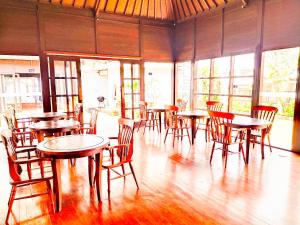a dining room with tables and chairs and windows at Merlyn Meadows Retreat in Munduk