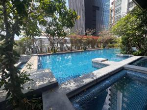 a large swimming pool with trees and buildings at NexStay Bangkok Appartment in Bangkok