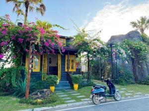 a scooter parked in front of a house with flowers at Vườn vua thanh thuỷ in Ðồng Phú