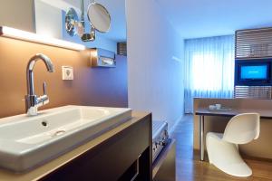 a bathroom with a sink and a white chair at Schwanen Boutique Hotel & Restaurant Metzingen in Metzingen +68 photos