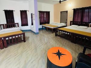 a room with three beds and a table in it at Comforts Bhairavi INN in Kalyānpur