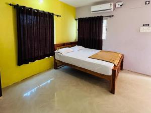 a bedroom with a bed in a room with yellow walls at Comforts Bhairavi INN in Kalyānpur