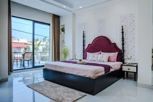 a bedroom with a large bed with a purple headboard at Villa Aura in Siliguri