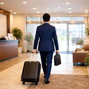 a man in a blue suit pulling a suitcase at Tetora Higashimuroran in Muroran