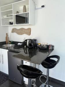 a kitchen with a counter with two black bar stools at Coastal Beach Apartments in Maputo