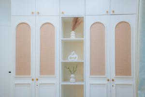 a white cabinet with shelves and vases on it at Villa Aura in Siliguri +165 photos