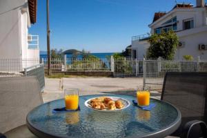 a table with a plate of food and two glasses of orange juice at ENDLESS BLUE WAVE in Paleo Tsifliki