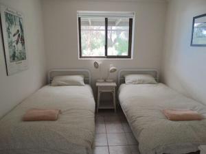 two twin beds in a room with a window at The Beach House, Kangaroo Island in Baudin Beach