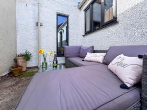 a purple couch with pillows on a patio at Rosemary Cottage in Mattishall
