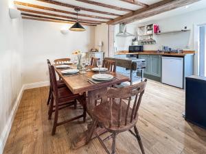 a kitchen and dining room with a wooden table and chairs at Rosemary Cottage in Mattishall