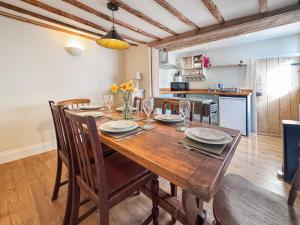 a dining room with a wooden table and chairs at Rosemary Cottage in Mattishall