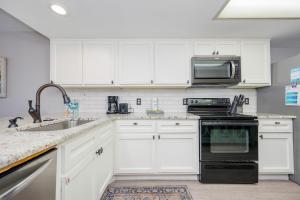 a kitchen with white cabinets and a black stove top oven at Wind Drift 604S condo in Orange Beach