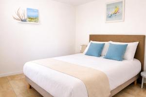 a bedroom with a large bed with blue pillows at Residence Clos des Aigrettes -Appartements a 30m du Port de La Cotiniere , Ile d Oleron -commerces et plages a pied in La Cotinière