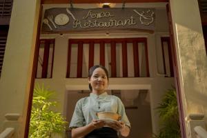 a woman holding a bowl in front of a door at La Rivière d' Angkor Resort in Siem Reap +158 photos