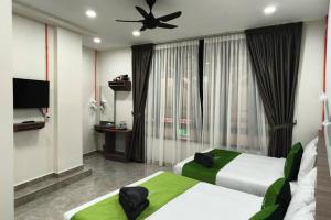 a hotel room with two beds and a ceiling fan at Cameron Green Inn Hotel in Brinchang