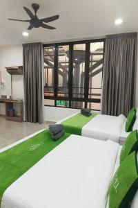 two beds in a bedroom with a ceiling fan at Cameron Green Inn Hotel in Brinchang +14 photos