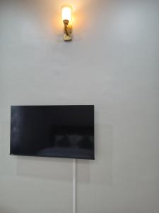 a television on a white wall with a light on it at Kibs Apartments in Dodoma