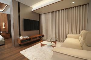 a living room with a couch and a tv at Hotel Bluebell in Kozhikode