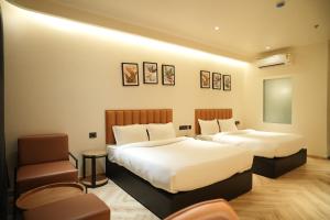 a hotel room with two beds and a chair at Vintclub Resort in Lucknow +56 photos
