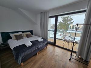 a bedroom with a bed and a large window at FLAUTA apartamenty in Iława