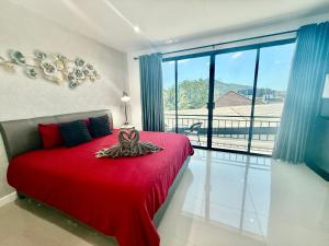 a bedroom with a red bed and a large window at TN KAMALA Room For Rent in Kamala Beach