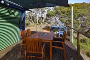 a wooden table and chairs on a deck with an umbrella at Georgina's place, Kangaroo Island in Brown Beach